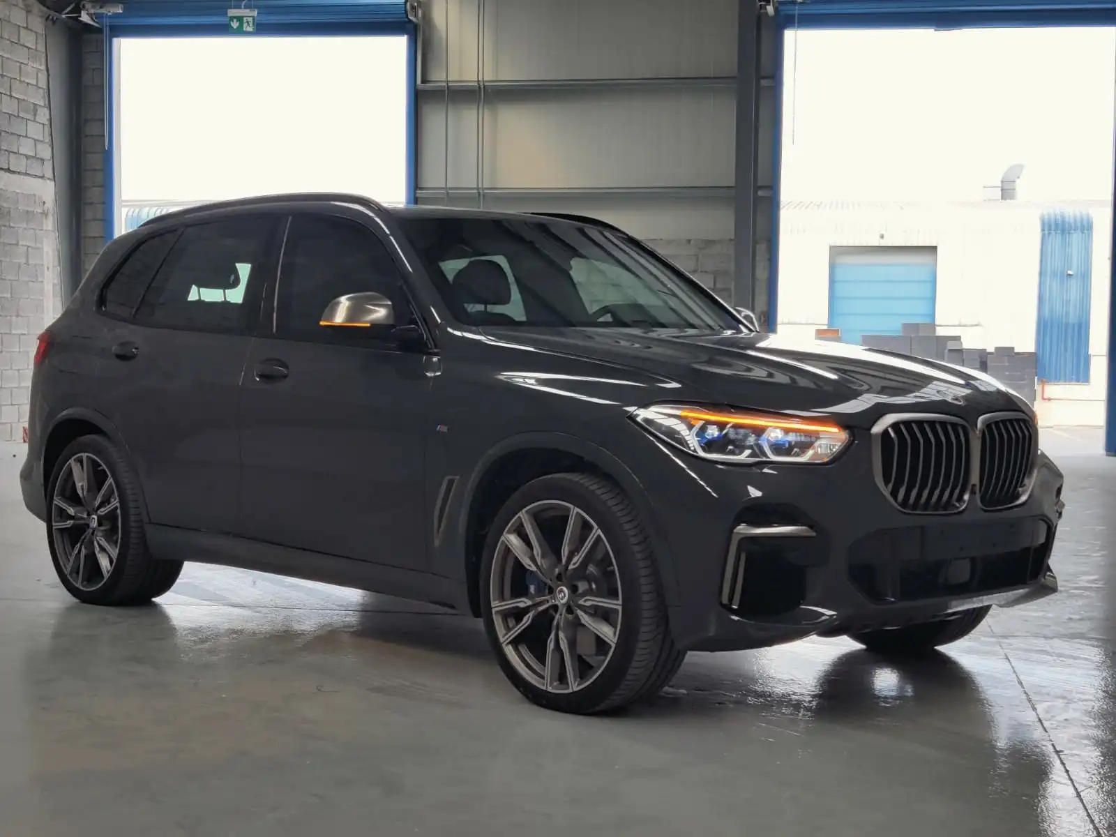 BMW X5 M50i grey armored luxury SUV front left exterior angle