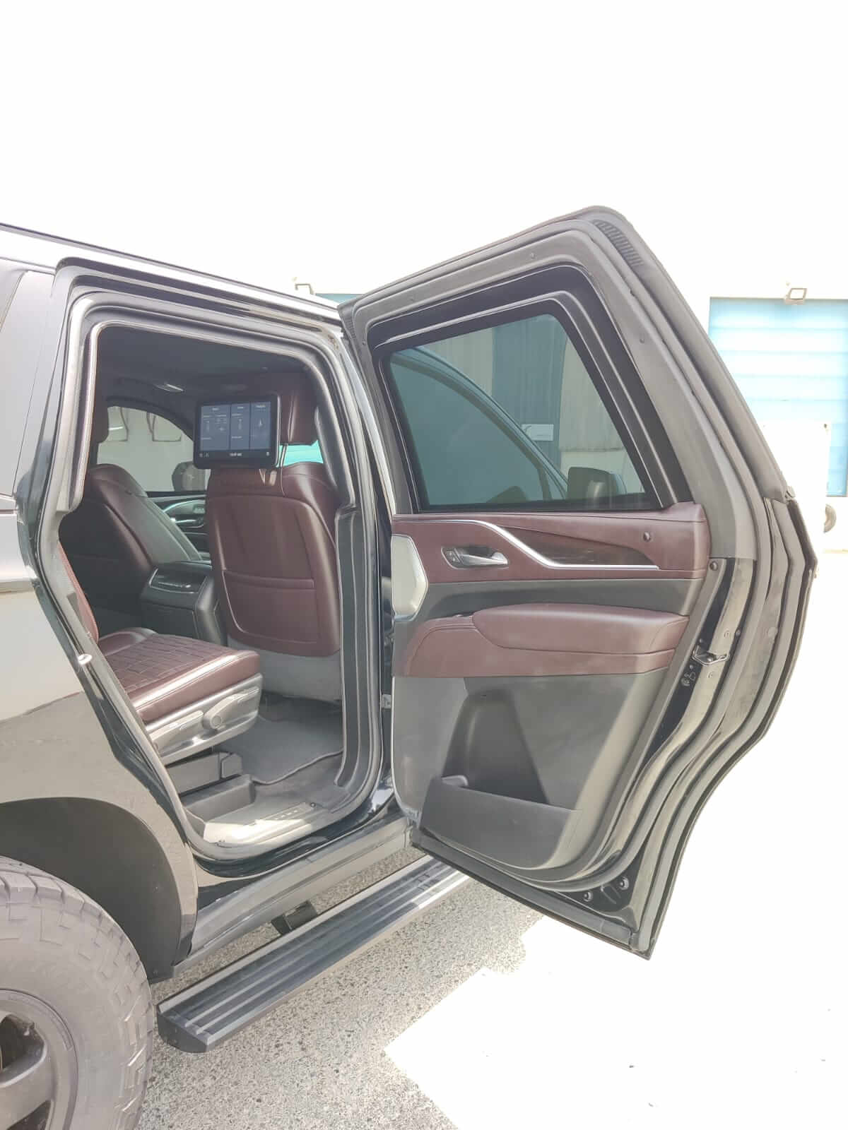 Cadillac Escalade armored luxury SUV rear left door open with screen