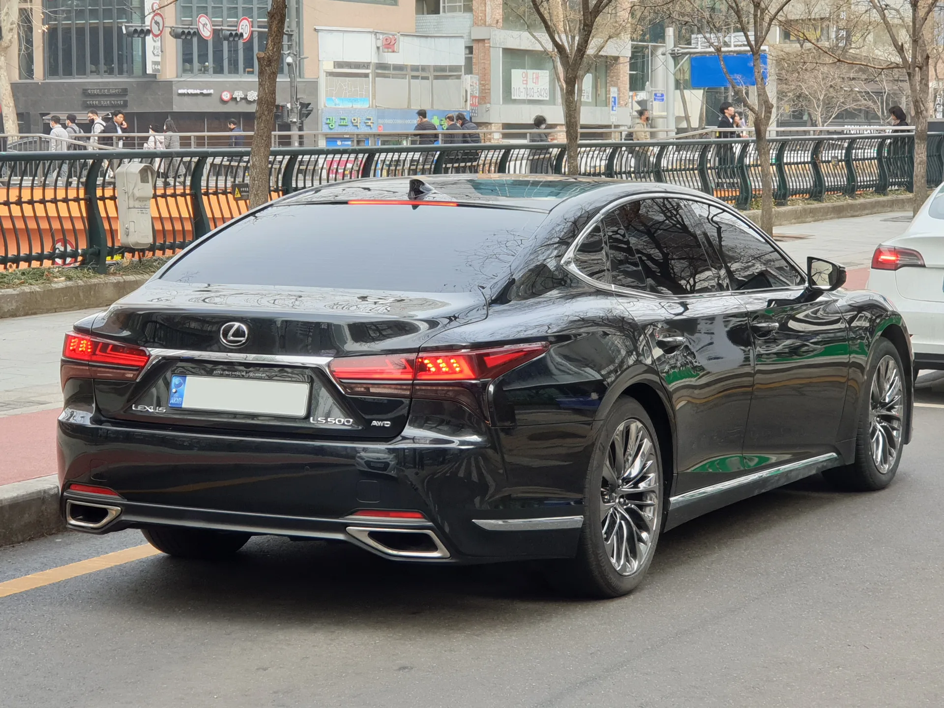 Black current-generation Lexus LS facelift sedan shown from the rear left