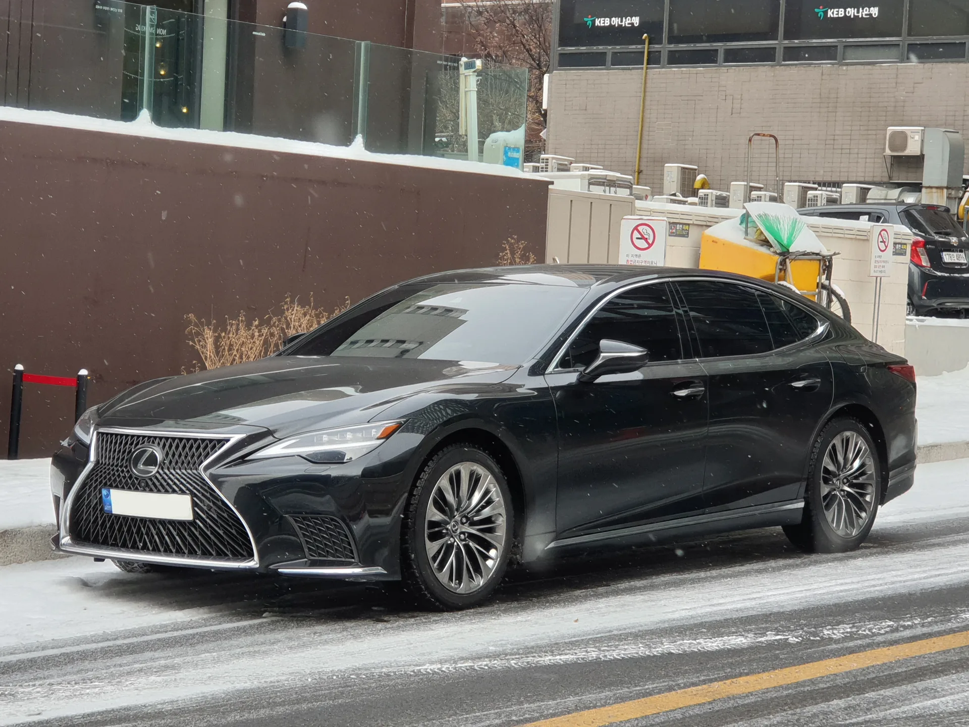 Black current-generation Lexus LS facelift sedan shown from the front left in winter