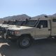 Row of Toyota Land Cruiser 70 Series tactical security vehicles in desert sand color with armored compartments